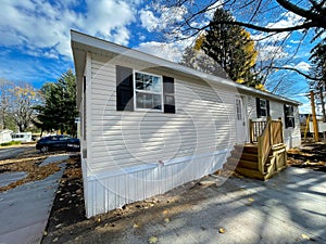 Side view of brand new prefab mobile home with for sale yard sign post in Rochester, New York
