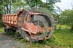 Side view of a broken old truck that has been badly damaged abandoned in the middle of a park