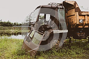 Side view of a broken old truck that has been badly damaged abandoned in the middle of a park with old vibes