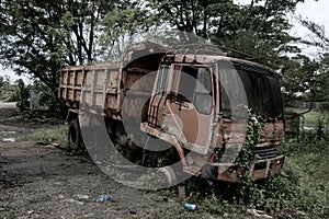 Side view of a broken old truck that has been badly damaged abandoned in the middle of a park with scary vibes