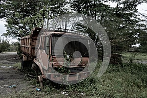 Side view of a broken old truck that has been badly damaged abandoned in the middle of a park with scary vibes