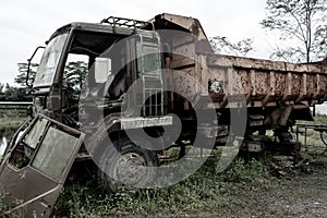 Side view of a broken old truck that has been badly damaged abandoned in the middle of a park with scary vibes