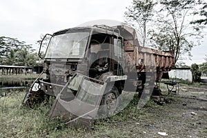 Side view of a broken old truck that has been badly damaged abandoned in the middle of a park with scary vibes