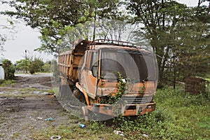 Side view of a broken old truck that has been badly damaged abandoned in the middle of a park with vintage vibes