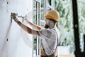 side view of builder in protective helmet and googles using spirit level at construction