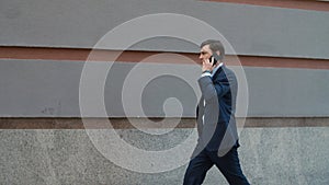 Side view business man having phone talk at street. Man walking to office