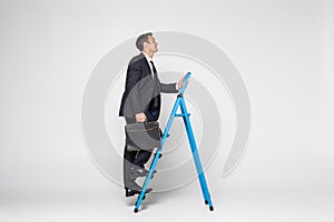 Side view of a businessman climbing a ladder, isolated on a white background