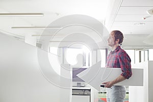 Side view of businessman holding arrow sign in creative office