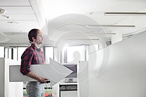 Side view of businessman holding arrow sign in creative office