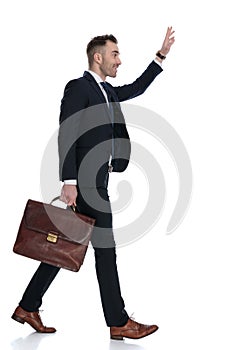 Side view of businessman holding briefcase and waving