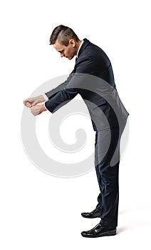 Side view of a businessman looking downwards and holding something isolated on white background