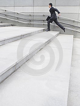 Side View Of Businessman Running Up Steps