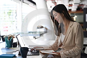 Side view of  businesswoman sitting in modern office and working with tablet computer.