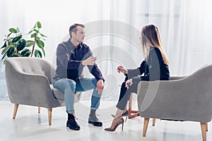 Side view of businesswoman in suit giving interview to journalist in office, they sitting