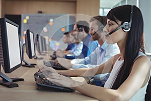 Side view of businesswoman typing on keyboard at call center