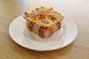 Side view of cake slice with icing, walnut, pumpkin seeds and dense filling