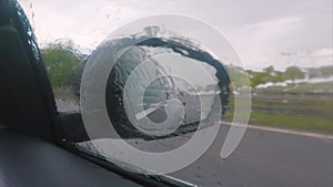Side view car mirror in rainy weather. High speed movement.