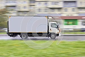 Side view of a cargo delivery truck blurred with an copy space on a blurred background in traffic