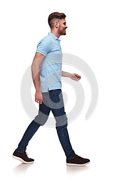 Side view of casual man in blue polo shirt walking