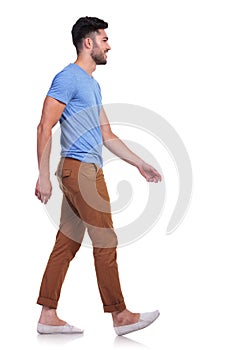 Side view of a casual man walking forward and smiling