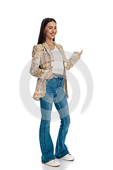 side view of casual young woman holding hand in pocket and presenting to side