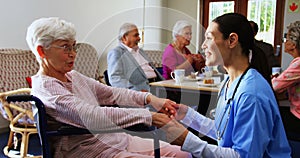 Side view of Caucasian female doctor consoling sad disabled senior woman at nursing home 4k