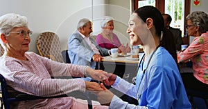 Side view of Caucasian female doctor consoling sad disabled senior woman at nursing home 4k