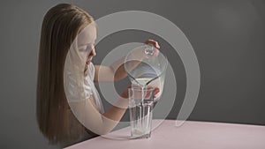 Side view Caucasian little girl drinks milk from a glass,