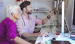 Male doctor showing medical reports on computer in a clinic room