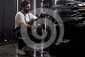 Side view on caucasian man auto mechanic worker polishing car at automobile repair and renew service station shop