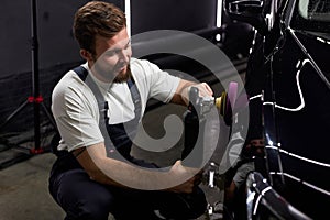 Side view on caucasian man auto mechanic worker polishing car at automobile repair and renew service station shop