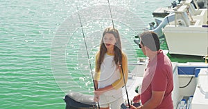 Side view of a Caucasian man and his teenage daughter holding fishing rods