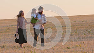 Side view Caucasian parents with child girl going in park. Family mother father with daughter walking along wheat field