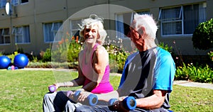 Side view of Caucasian senior couple exercising with dumbbells in the garden of nursing home 4k