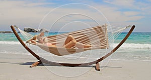 Side view of Caucasian woman relaxing in a hammock at beach 4k