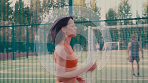 Side view of caucasian woman running in orange sportswear doing cardio workout at sports ground.