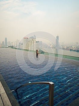 Side view of a caucasian woman standing in an infinity pool on a rooftop in Bangkok, Thailand