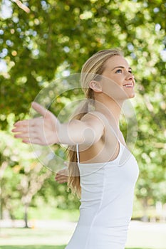 Side view of cheerful attractive woman doing yoga spreading her arms