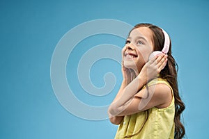 Side view of cheerful girl in headphones listening music