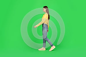 Side View Of Cheerful Woman Walking Posing Over Green Background