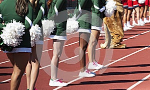 Side view of cheerleaders standing on the track infront of the stands during a football game