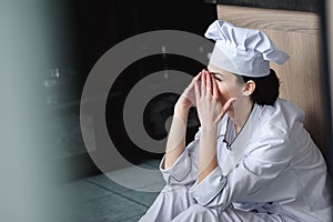 side view of chef crying and sitting on floor