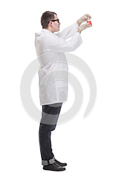 Side view of chemist holding up beaker of red chemical in the laboratory