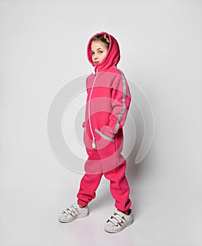 side view of a child girl in a fleece warm hooded suit with a hood and reflective stripes. the girl is standing sideways