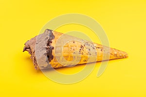 Side view chocolate flavor ice cream cone with some bites on yellow background