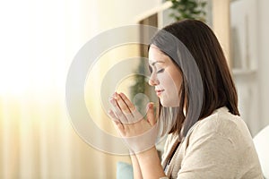 Side view of a woman praying at home photo