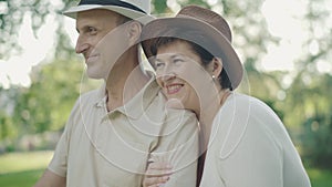 Side view close-up of cheerful mid-adult couple enjoying sunset in summer park. Portrait of happy Caucasian family