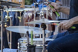 Side view close-up of dummer playing drum kit outdoors, hands and torso only.