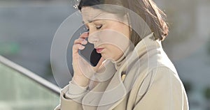 Side view close-up face of upset Caucasian woman talking on the phone and crying. Pretty stressed businesswoman having