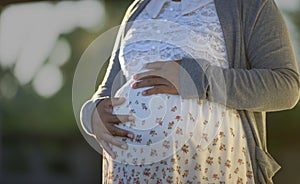 Side view close-up of pregnant woman touching her belly. Pregnancy health & wellbeing concept